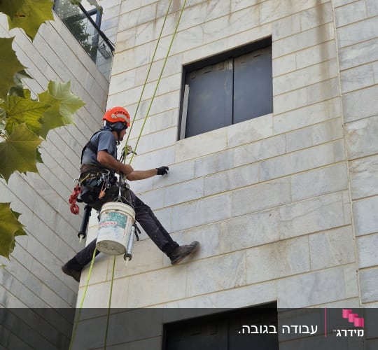 אדם על חבל עובד על קיר בניין